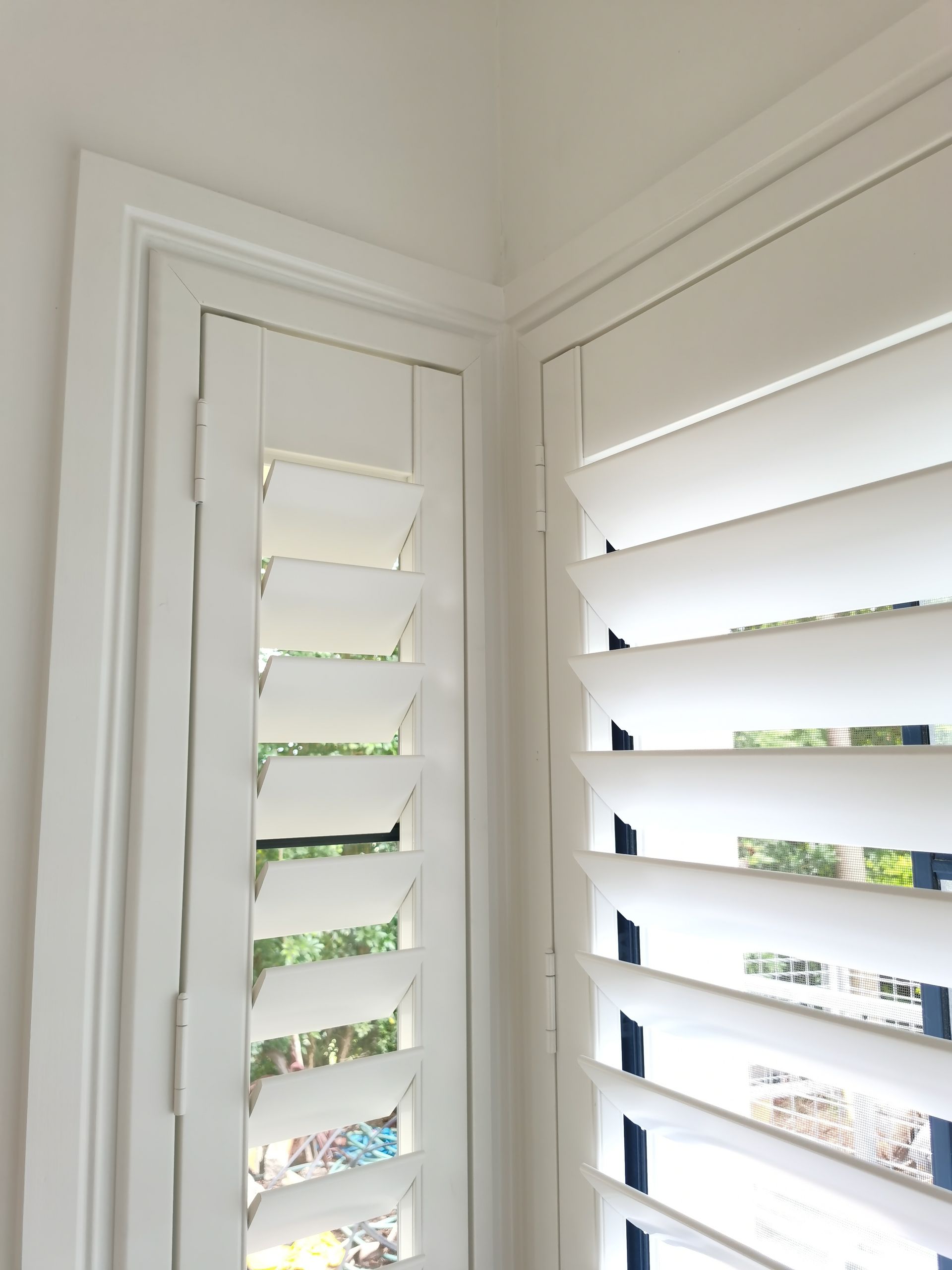 A close up of a window with white shutters on it