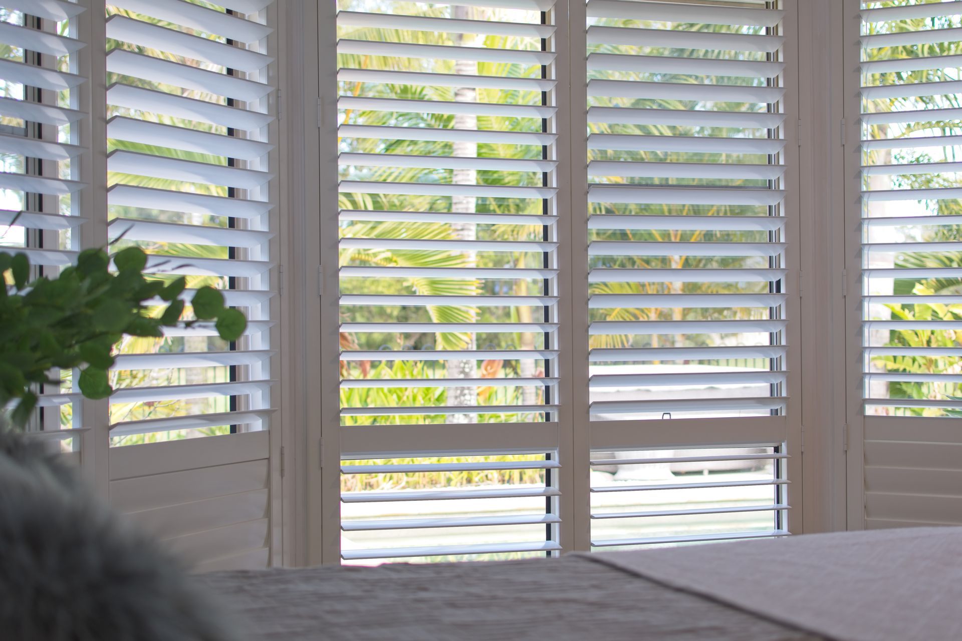 A bedroom with a bed and shutters on the windows