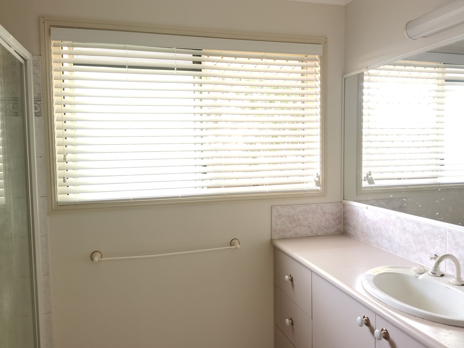 A bathroom with a sink and a window with blinds