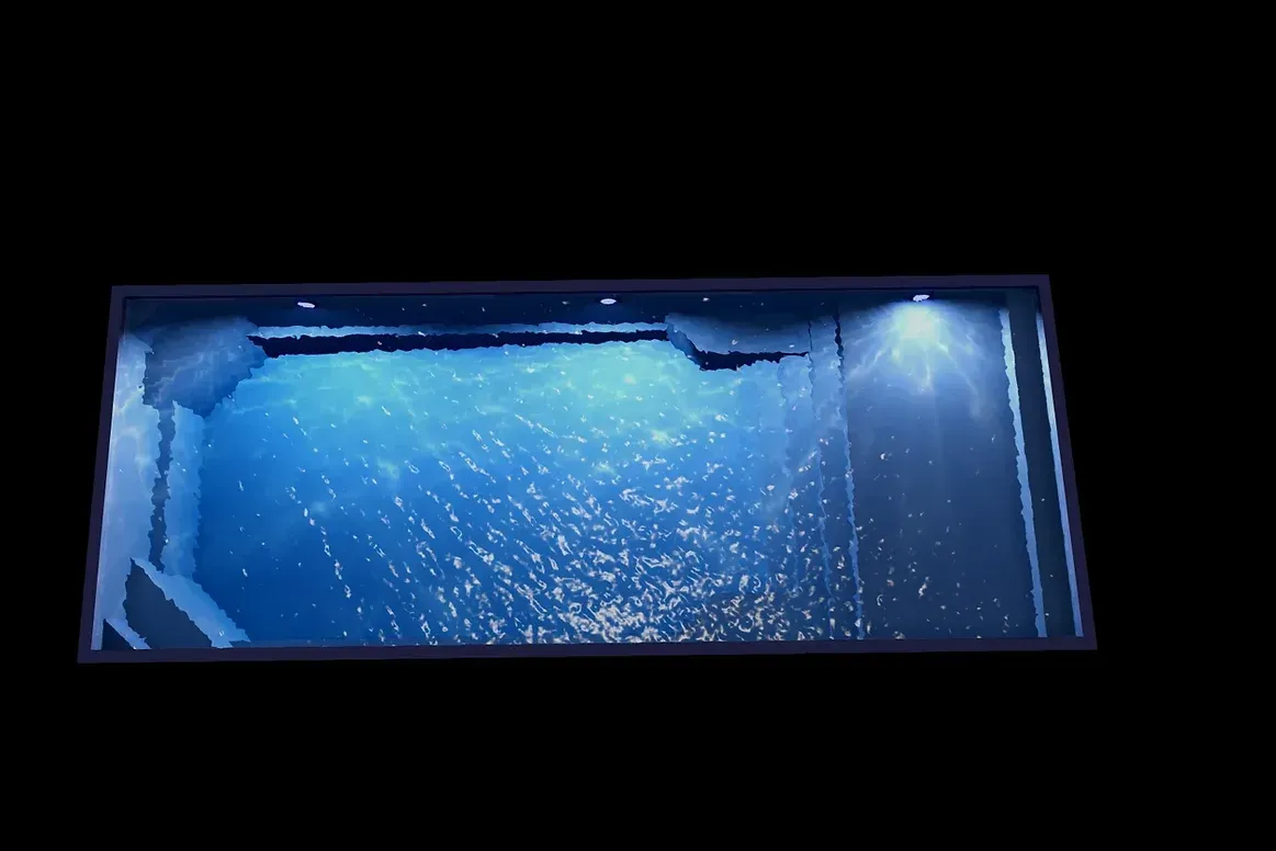 A swimming pool is lit up at night with blue lights