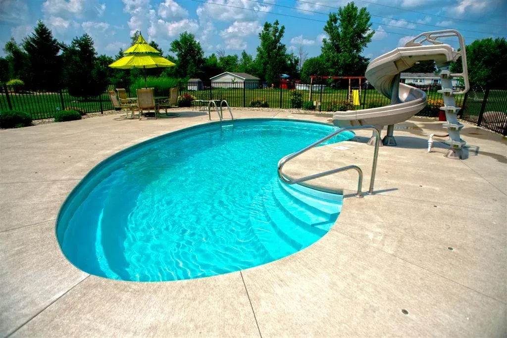 A swimming pool with a slide and umbrellas in the background