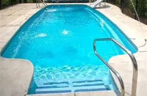 A large swimming pool with stairs leading to it and a slide.