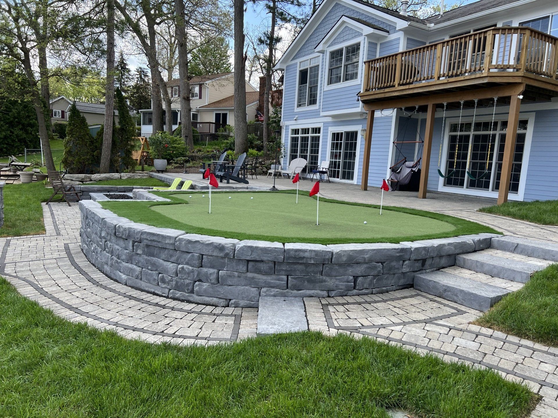 There is a putting green in the backyard of a house.