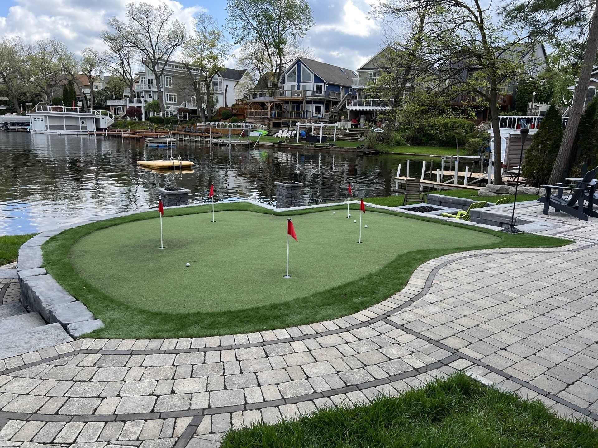 A putting green in a backyard next to a body of water.