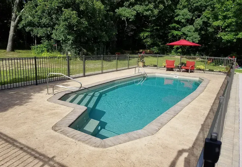 A large swimming pool surrounded by chairs and an umbrella