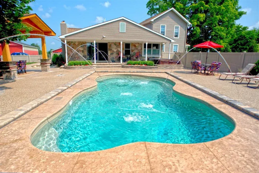 A large swimming pool is in the backyard of a house.