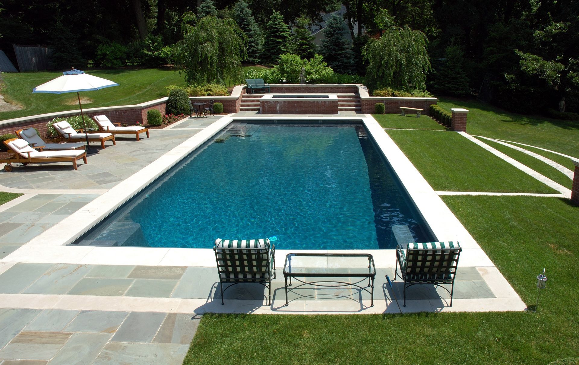 A large swimming pool surrounded by chairs and umbrellas