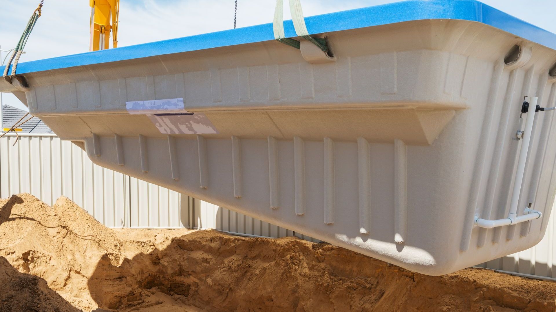 A large swimming pool is being lifted into the ground by a crane.