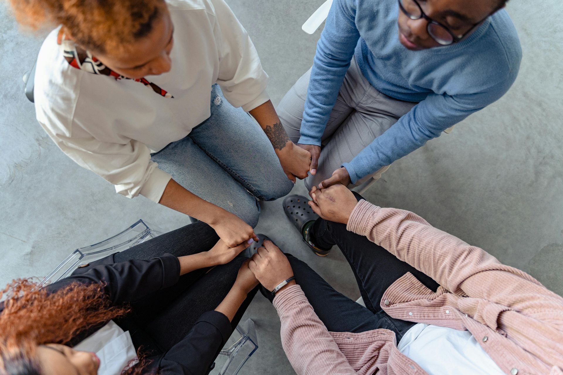 Five people sit in a circle, stacking hands together in a teamwork gesture.
