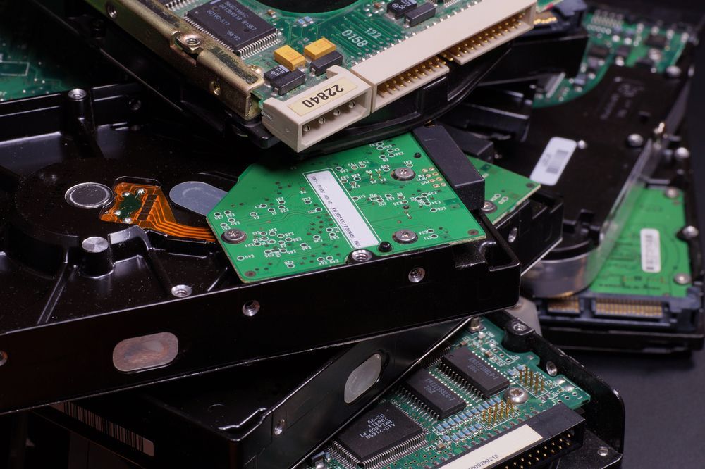 Pila di dischi rigidi e circuiti stampati di computer smontati.