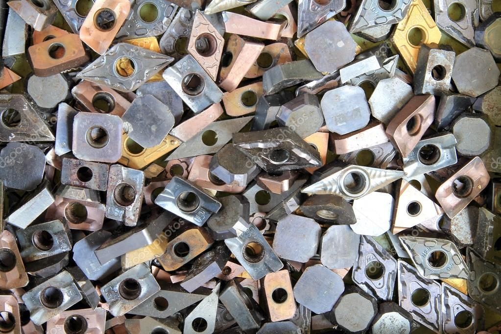 Inserti da taglio in metallo assortiti, di varie forme, dimensioni e colori, sparsi uno vicino all'altro.