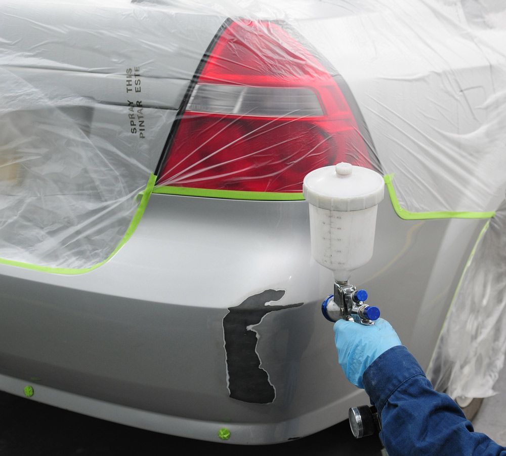 A Person is Spraying Paint on the Back of a Car — Shane’s Car Detailing & Office Cleaning in Taminda NSW