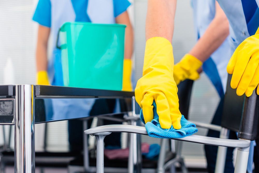 A Person is Wearing Yellow Gloves is Cleaning a Table With a Cloth — Shane’s Car Detailing & Office Cleaning in Manilla, NSW