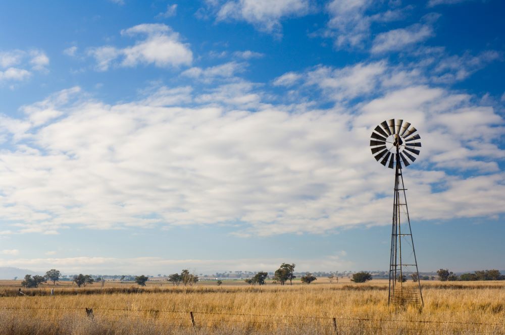 A Windmill in the Middle of a Field With a Blue Sky in the Background — Shane’s Car Detailing & Office Cleaning in Manilla, NSW
