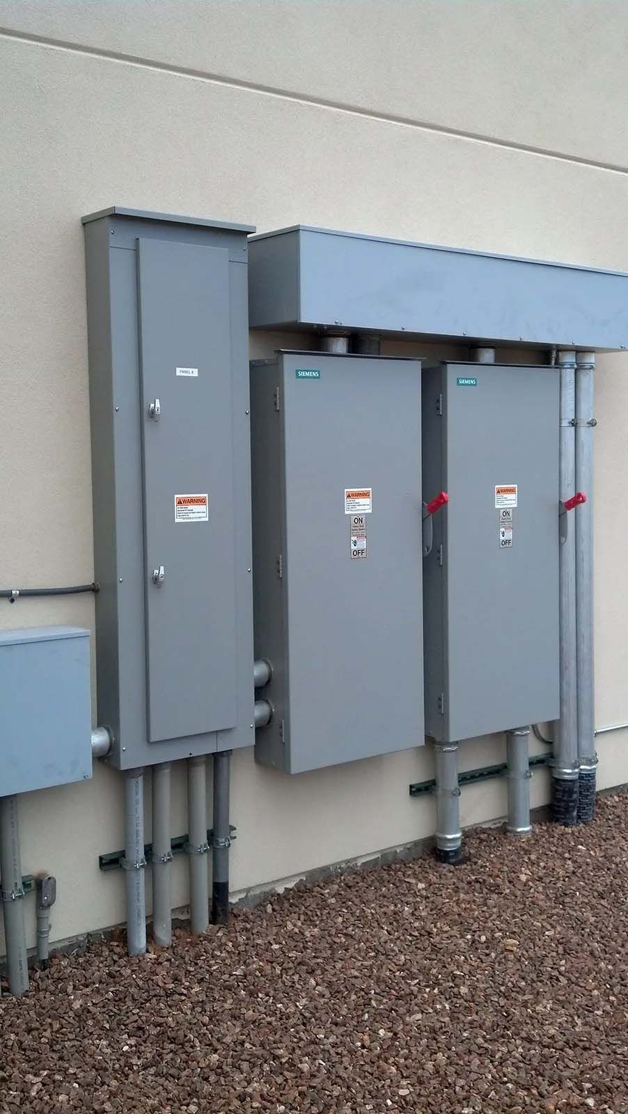 A row of electrical boxes on the side of a building.