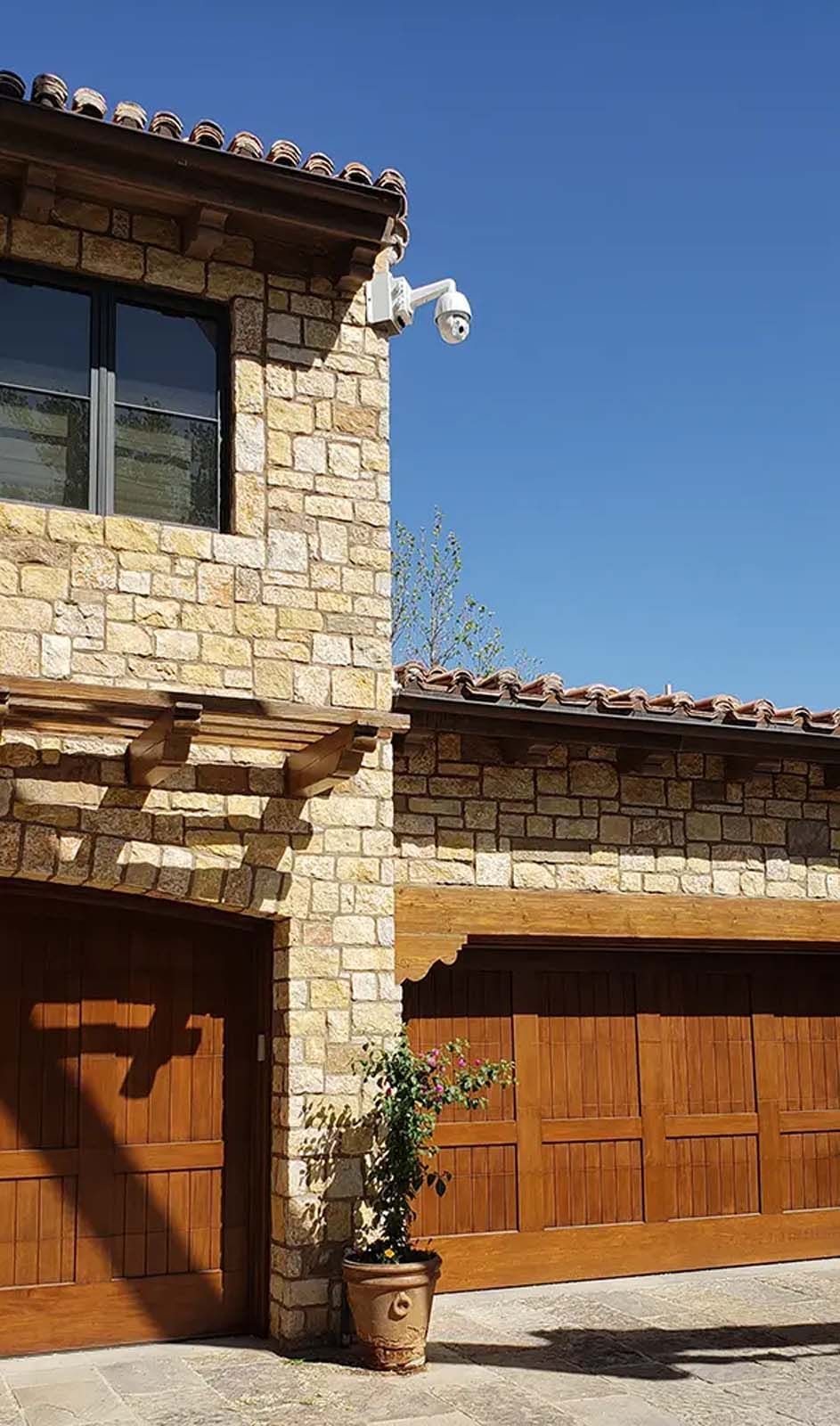 A house with two garage doors and a potted plant in front of it.