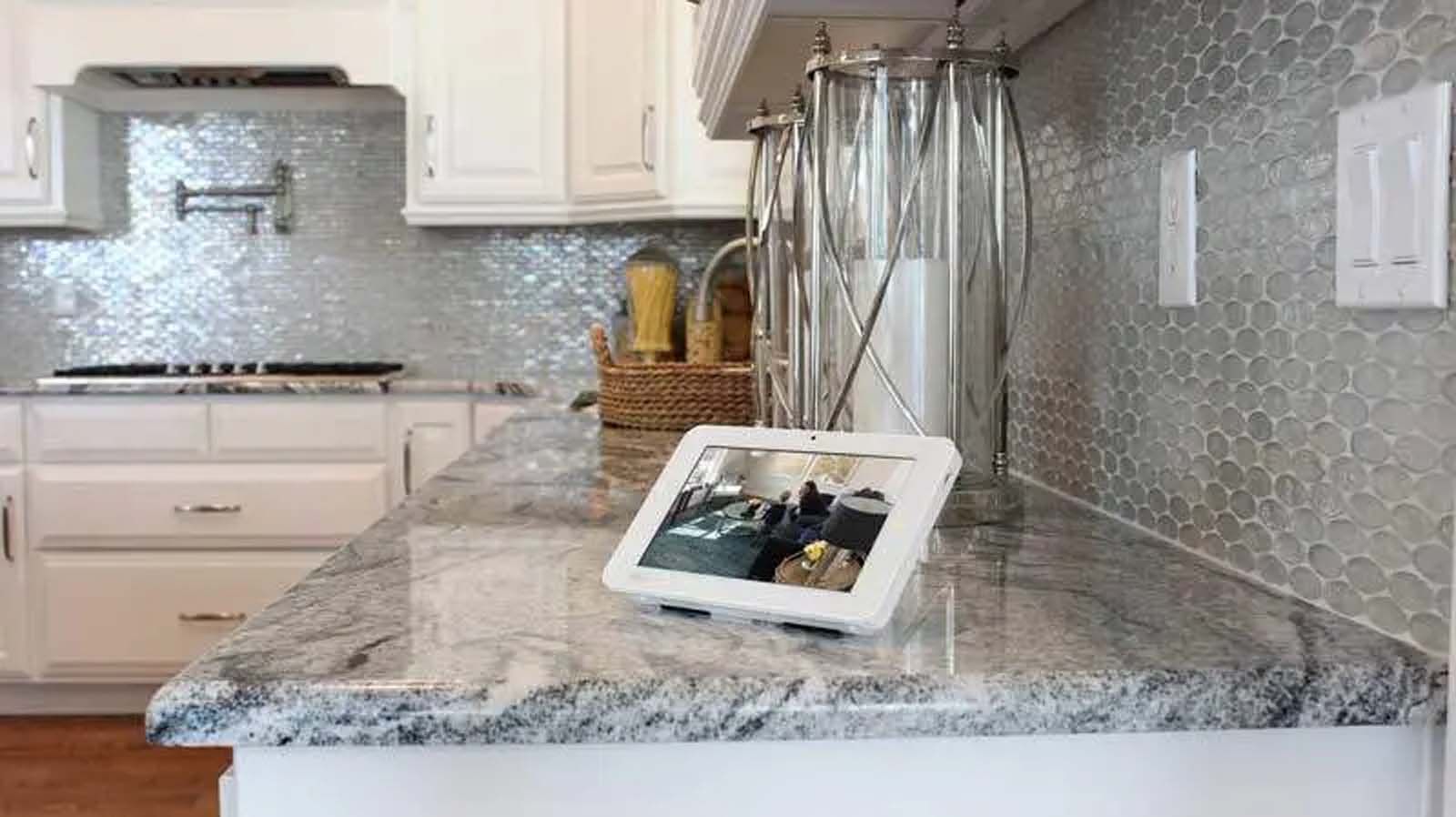 A tablet is sitting on top of a granite counter in a kitchen.