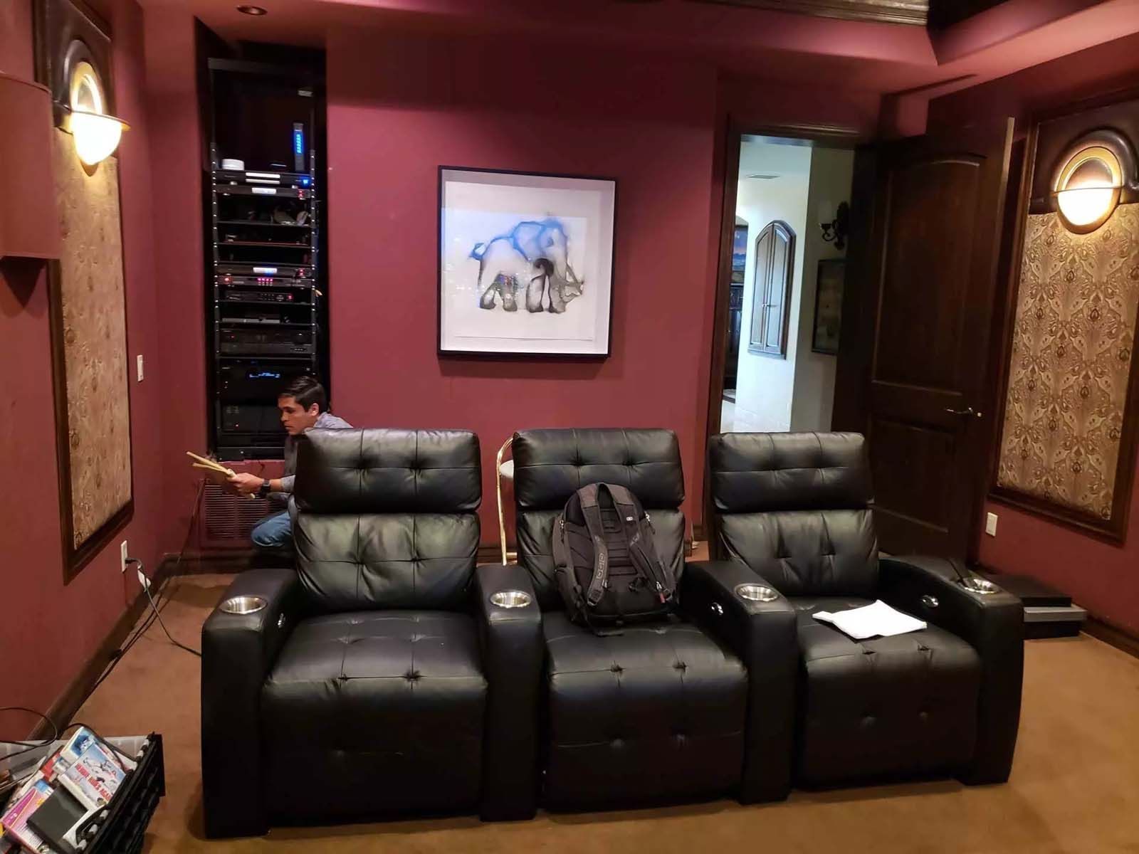 A man is sitting in a home theater watching a movie.