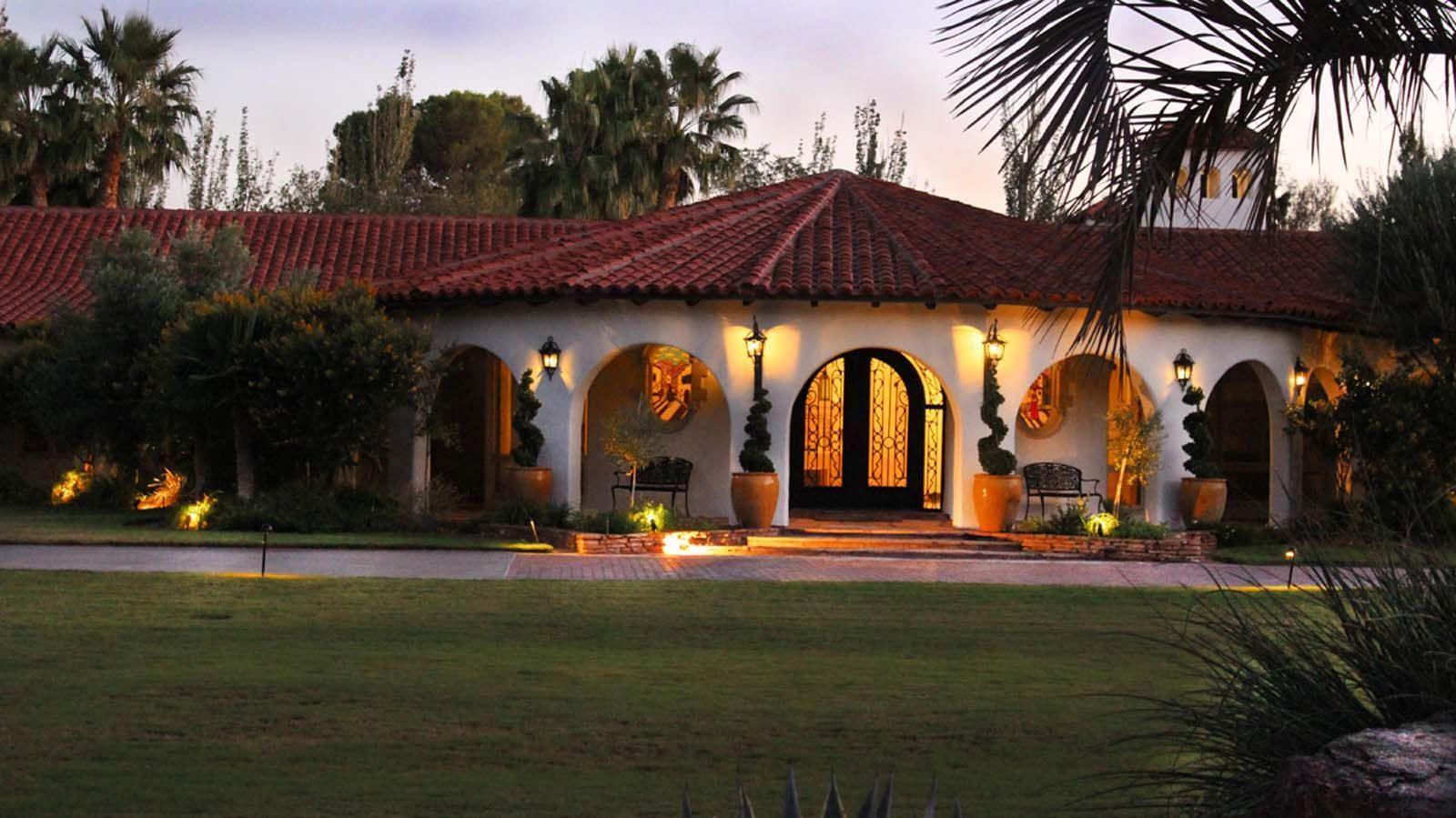 A large house with a red tile roof is lit up at night