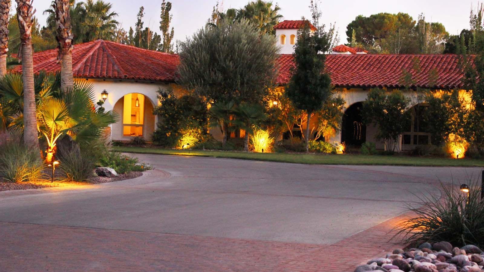 A large house with a red tile roof is lit up at night