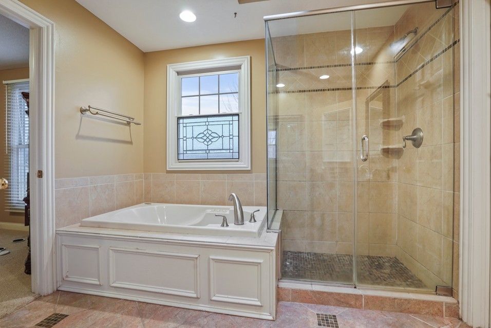 Modern bathroom with glass shower, gray tile, wooden floor, and light gray cabinetry.