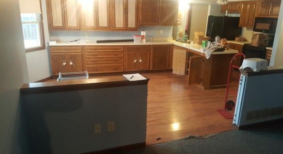 Modern white kitchen with island, metal chairs, round table, and open shelves.