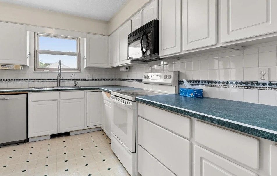 Bright white kitchen with island, cabinets, and stainless steel appliances.