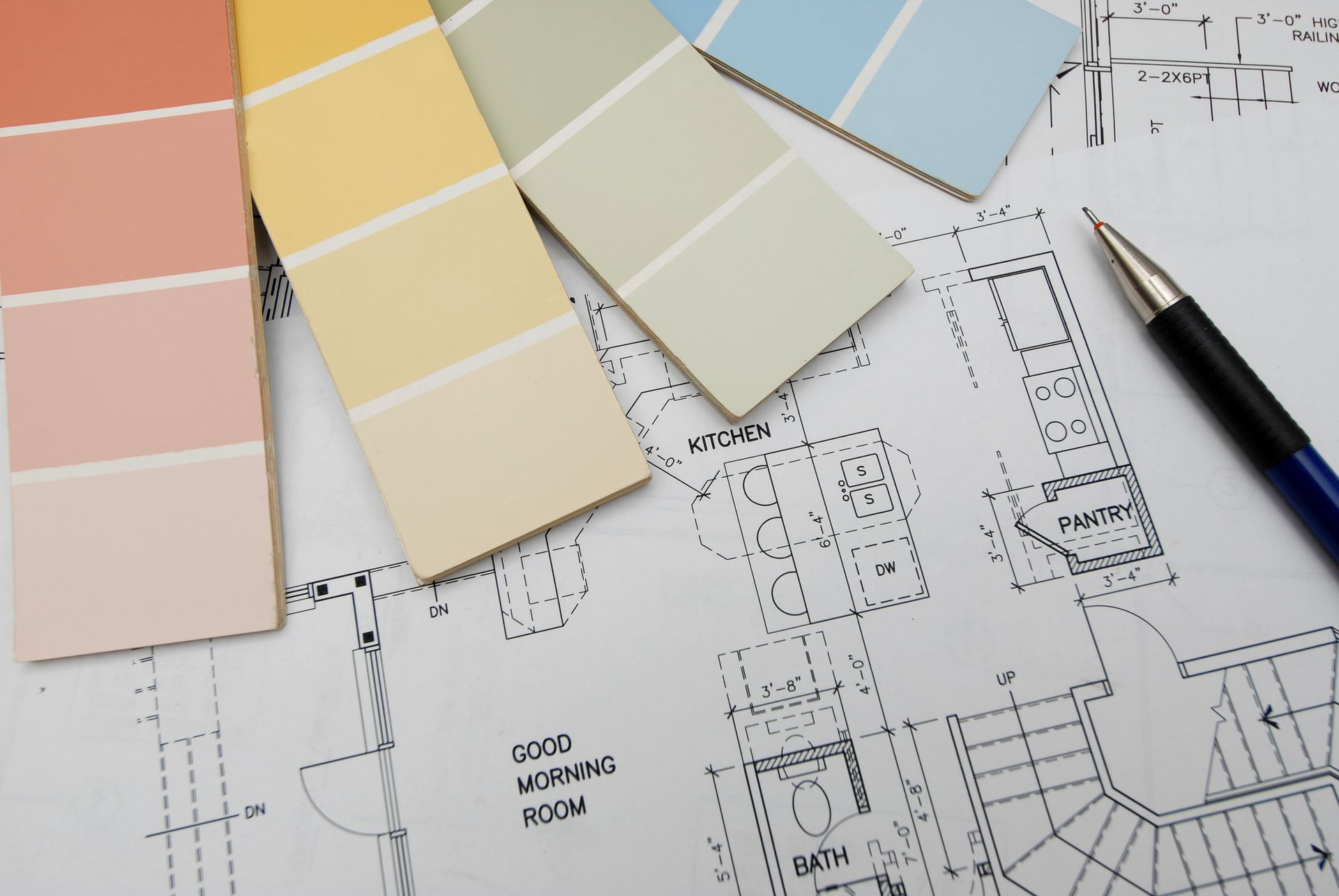 Color swatches over a blueprint with a pen, ready for interior design planning.