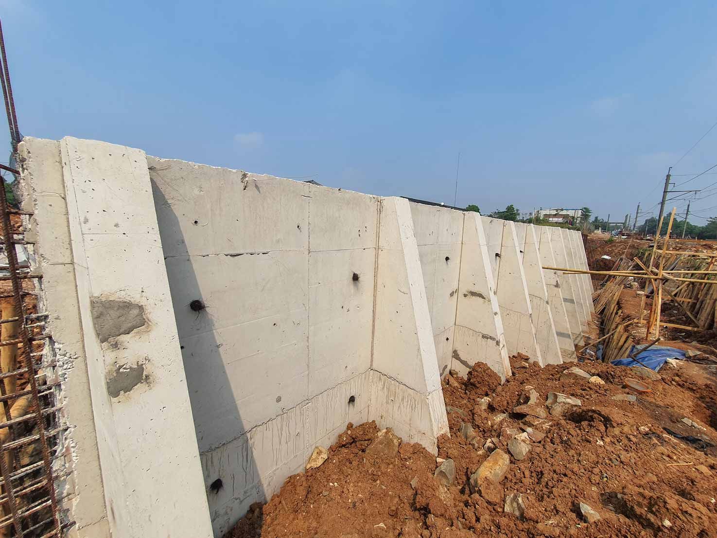 Concrete retaining wall on a dirt construction site under a clear blue sky