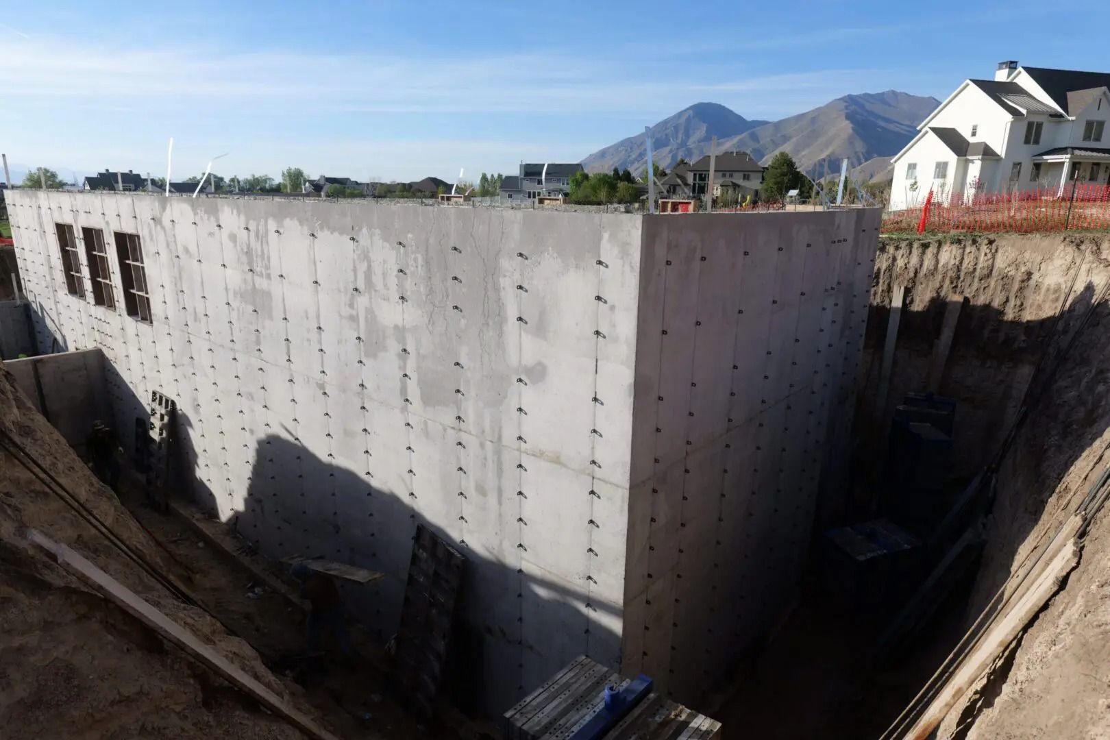 Concrete foundation walls in a deep excavation with mountains and houses in the background