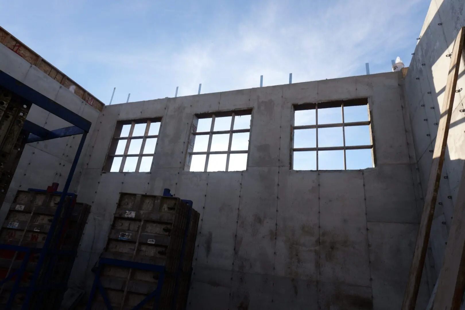 Partially built concrete room with large windows and stacked materials inside