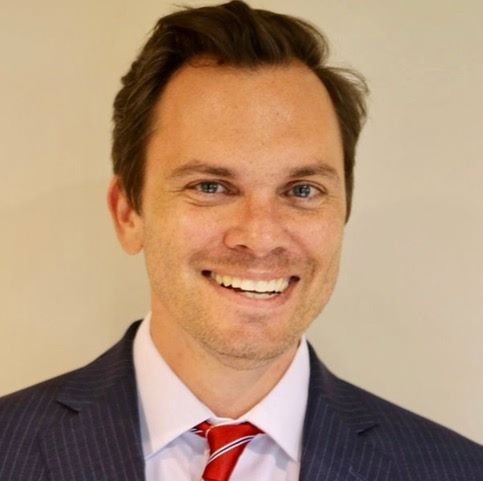 A man in a suit and tie is smiling for the camera