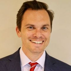 A man in a suit and tie is smiling for the camera