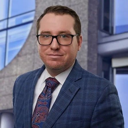 A man in a suit and tie is standing in front of a building.
