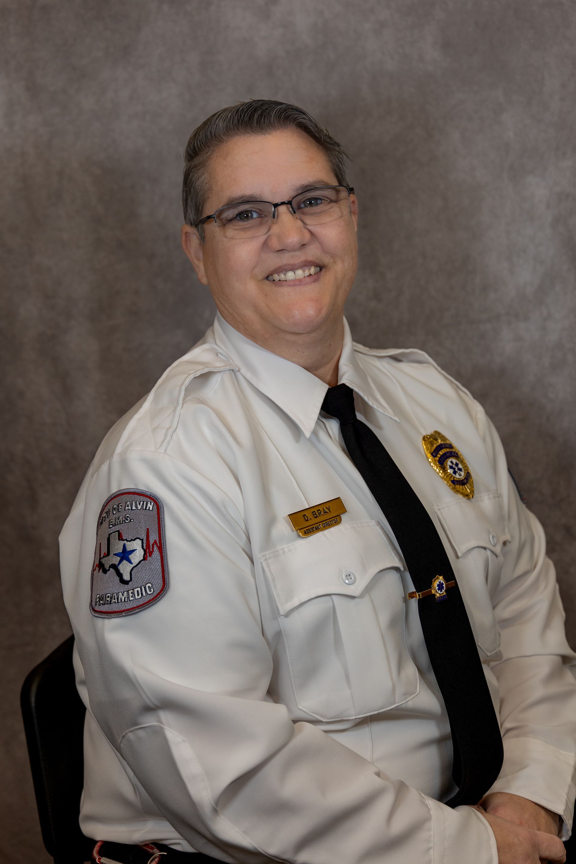 A woman in a white shirt and black tie is sitting in a chair.