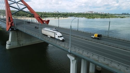 White truck and yellow car crossing a modern bridge over calm water