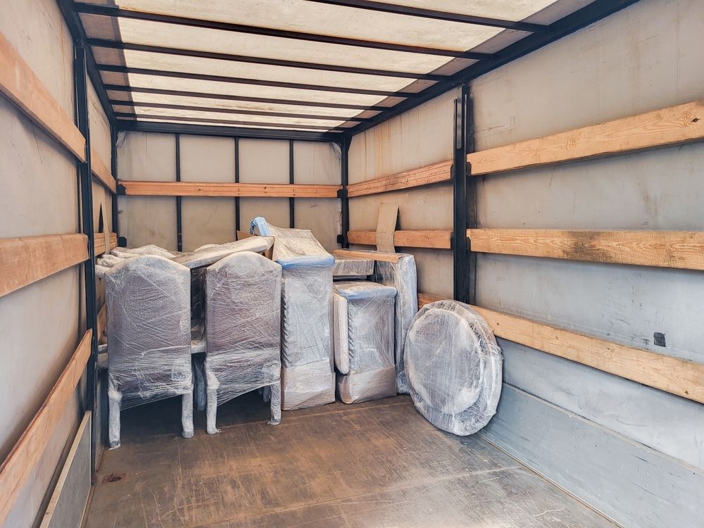 Empty moving truck with several wrapped and covered furniture items inside
