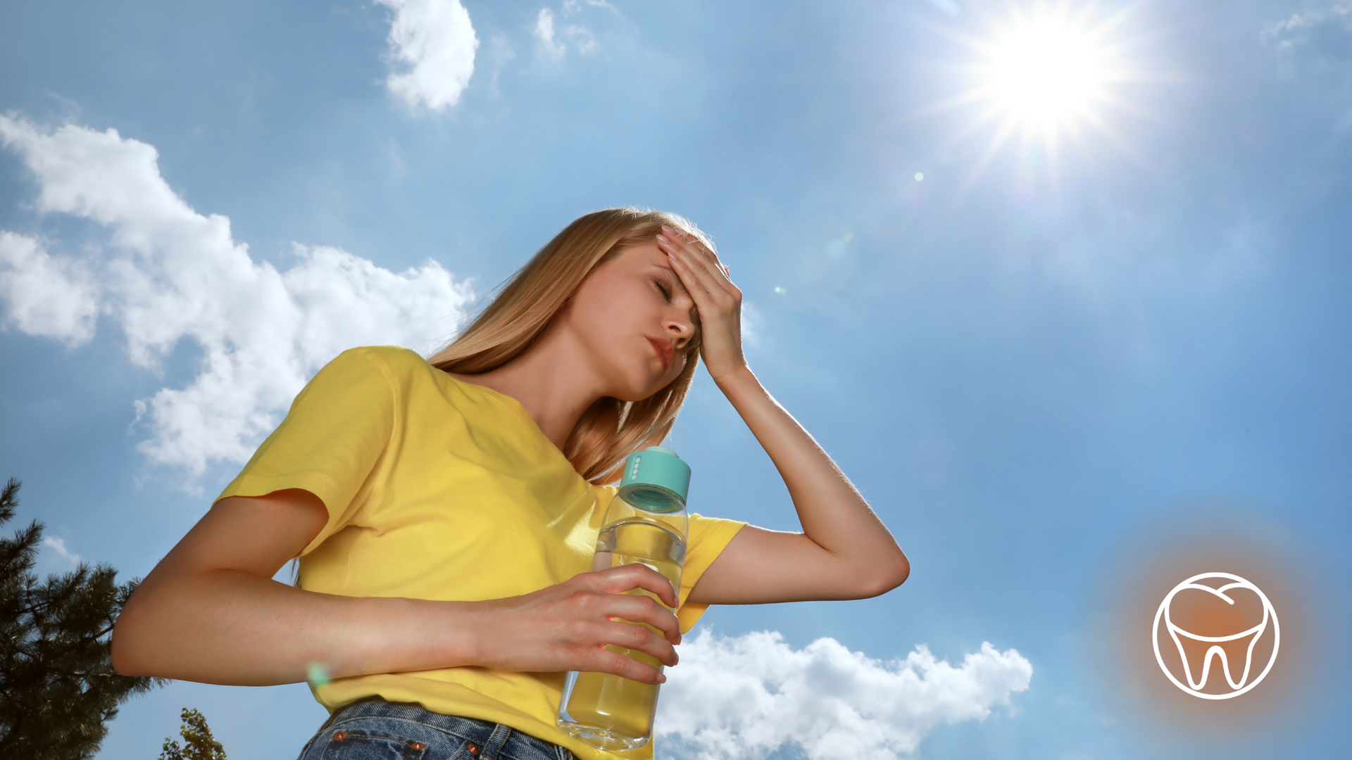 A woman in a yellow shirt is holding a bottle of water.