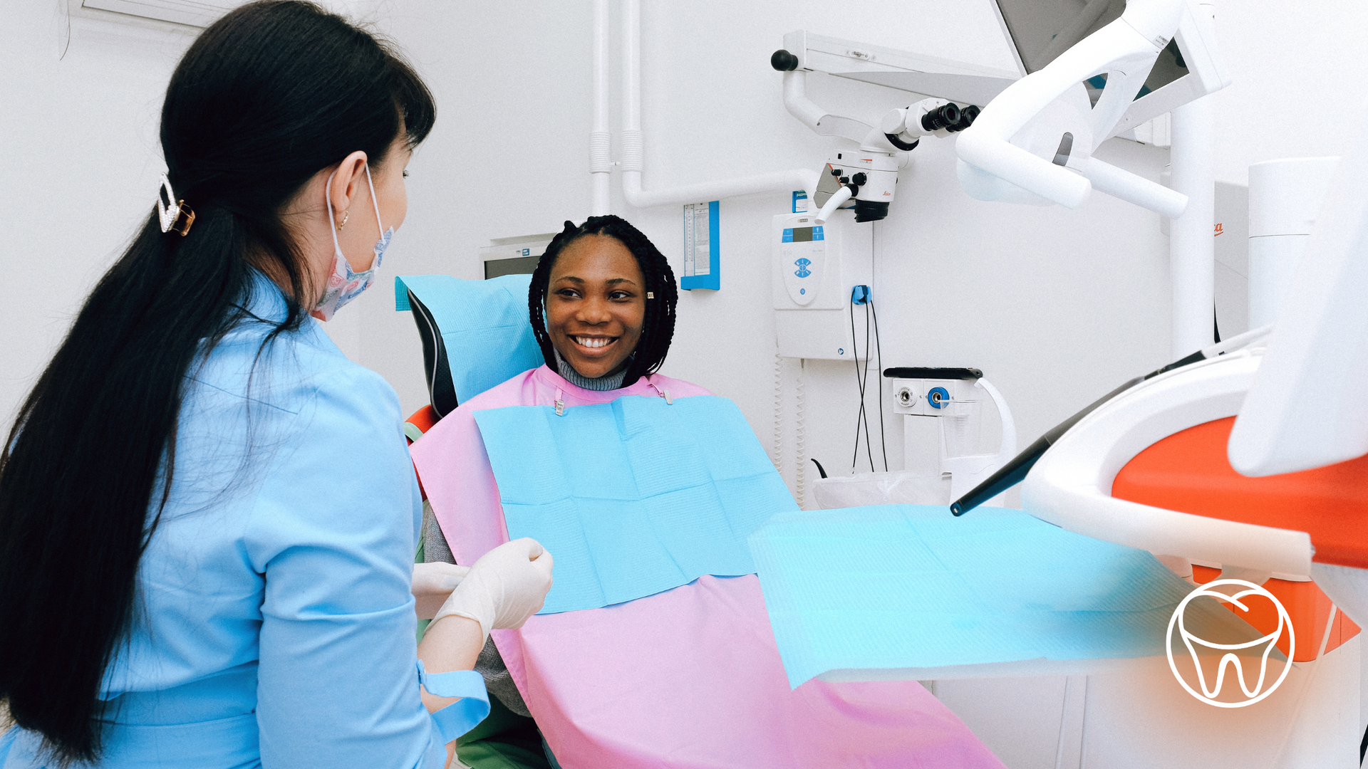 A woman is sitting in a dental chair talking to a dentist.