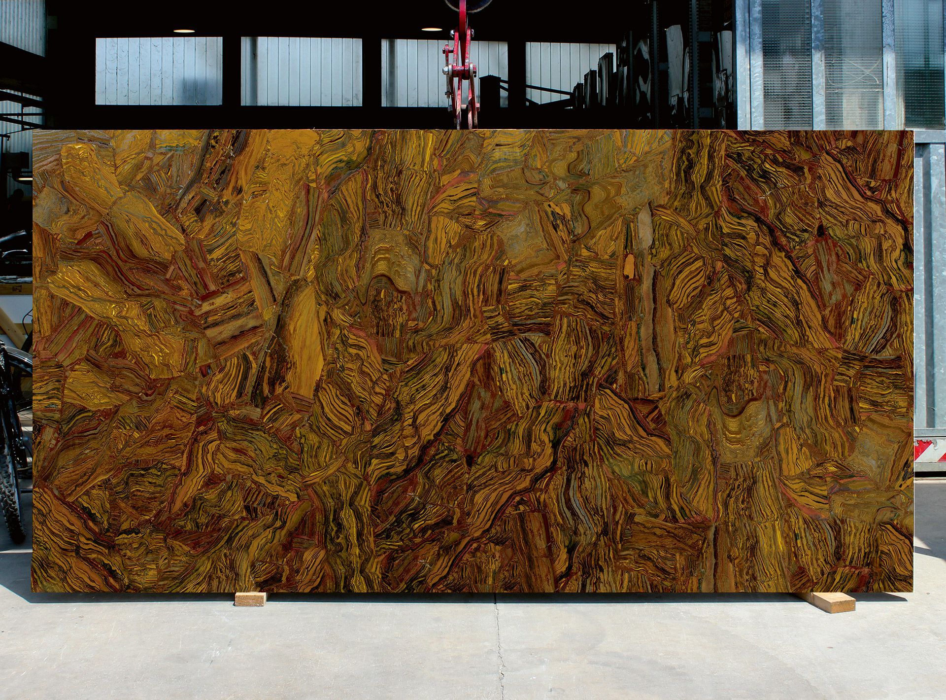 Large abstract brown-and-gold textured panel displayed on wooden supports indoors.