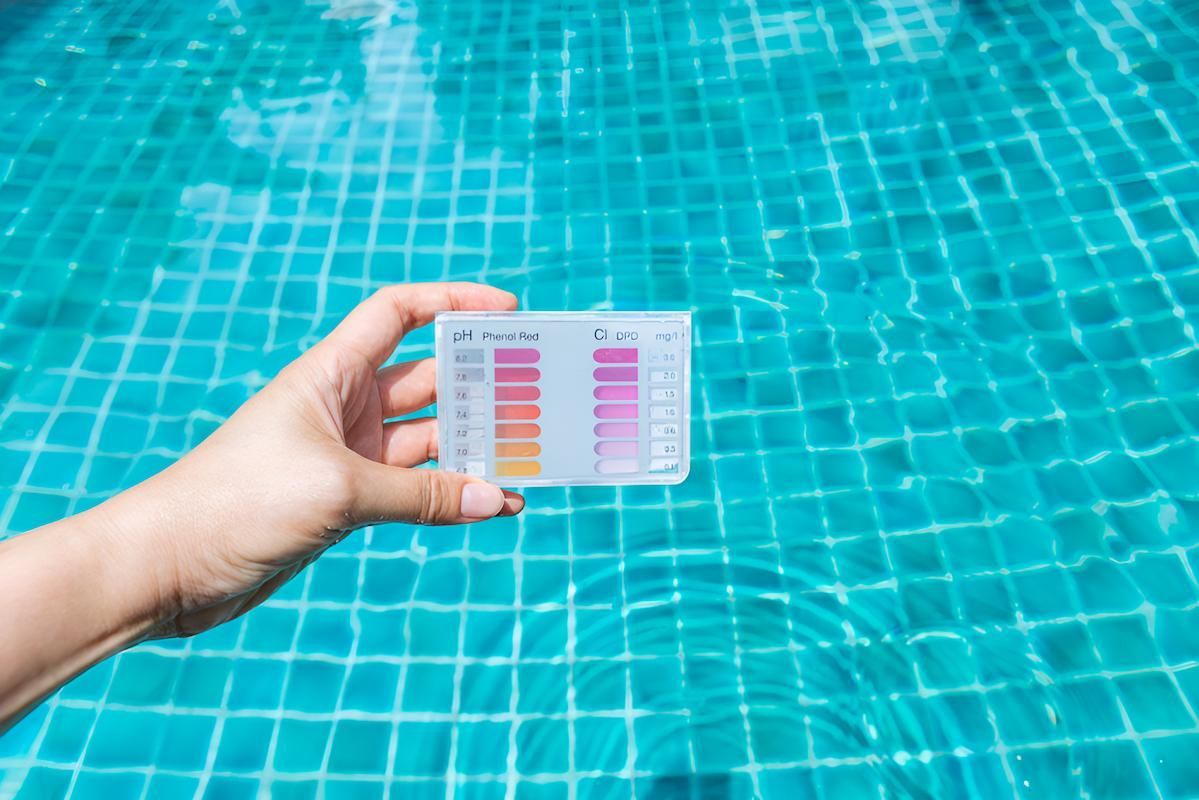 A Person is Holding a Test Kit in Front of a Swimming Pool — Sun City Pools In Hyde Park, QLD