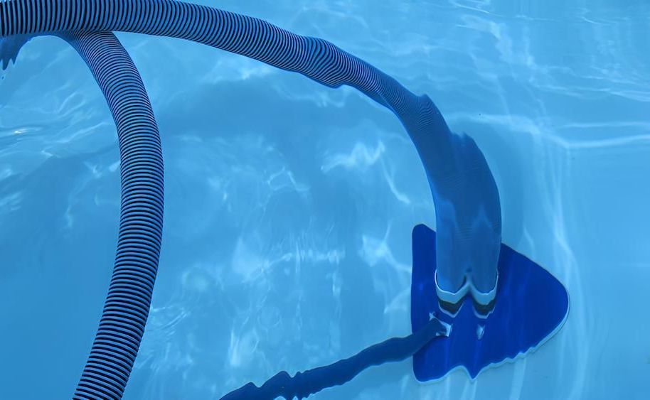 A Vacuum Cleaner is Being Used to Clean a Swimming Pool — Sun City Pools In Hyde Park, QLD