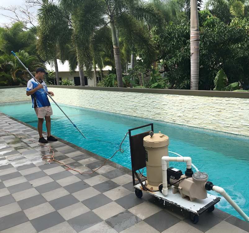 A Man is Cleaning a Swimming Pool With a Vacuum Cleaner — Sun City Pools In Bohle Plains, QLD