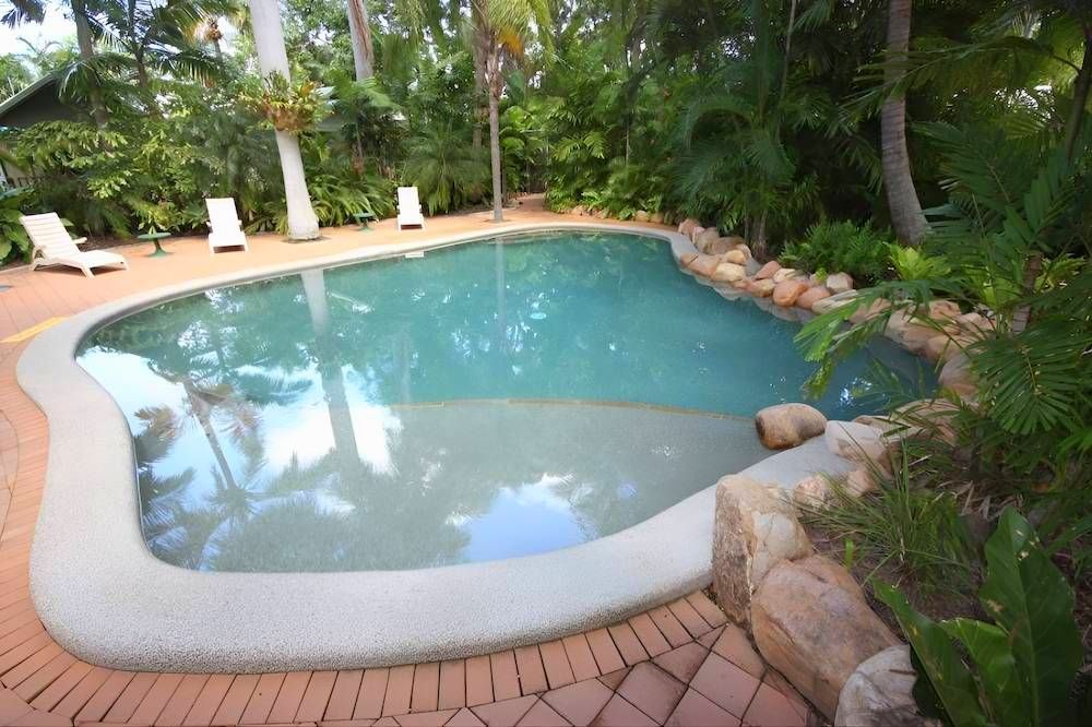 A Large Swimming Pool Surrounded by Trees and Rocks — Sun City Pools In Hyde Park, QLD