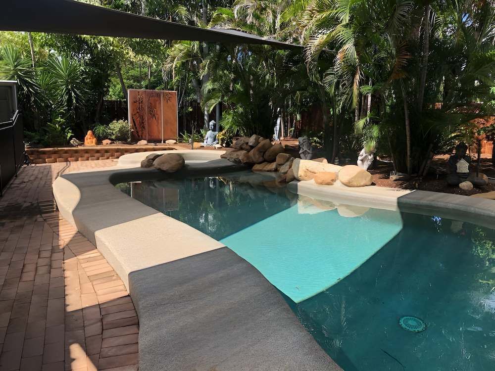 A Large Swimming Pool Surrounded by Trees and a Brick Patio — Sun City Pools In Hyde Park, QLD
