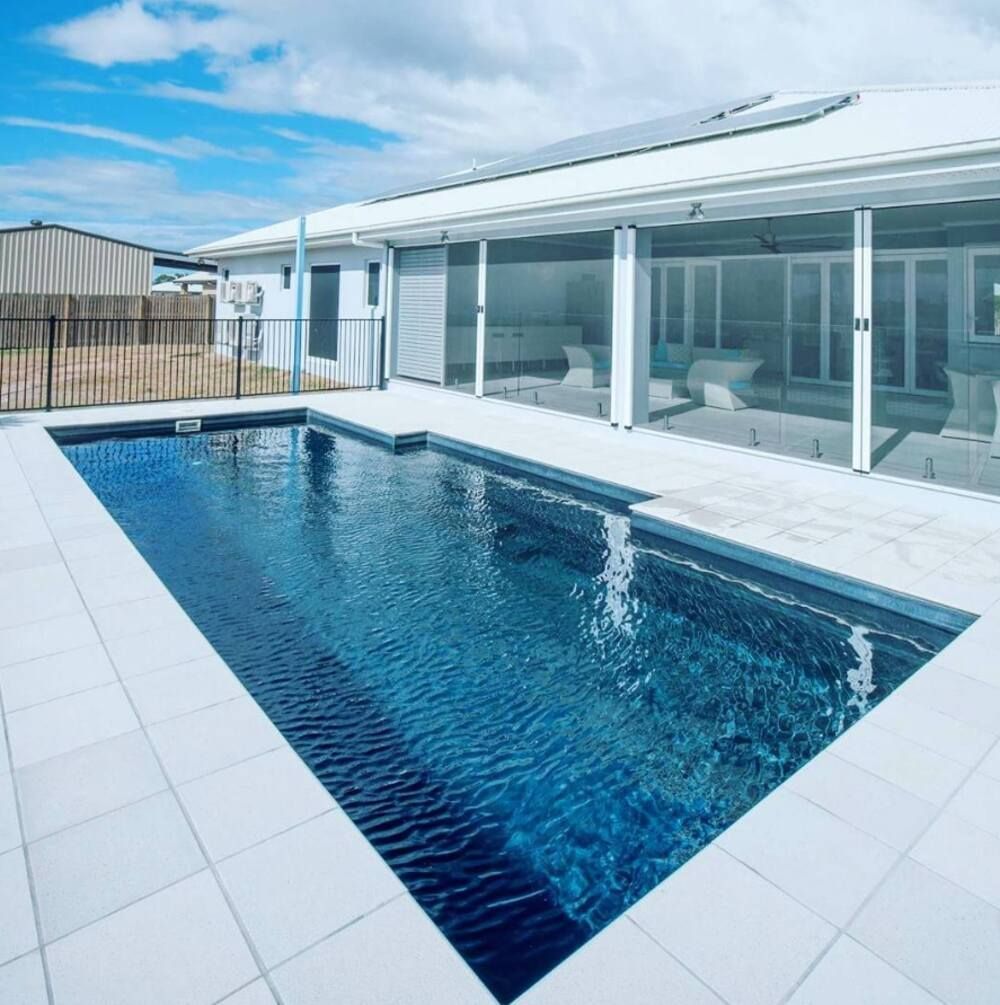 A Large Swimming Pool in Front of a House — Sun City Pools In Mount Louisa, QLD
