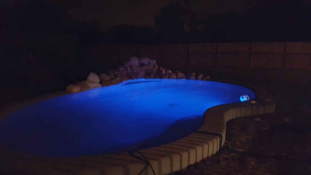 A Swimming Pool is Lit Up at Night With Blue Lights — Sun City Pools In Hyde Park, QLD