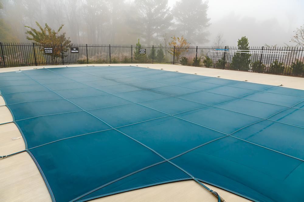 A Swimming Pool With a Blue Cover on It on a Foggy Day — Sun City Pools In Hyde Park, QLD