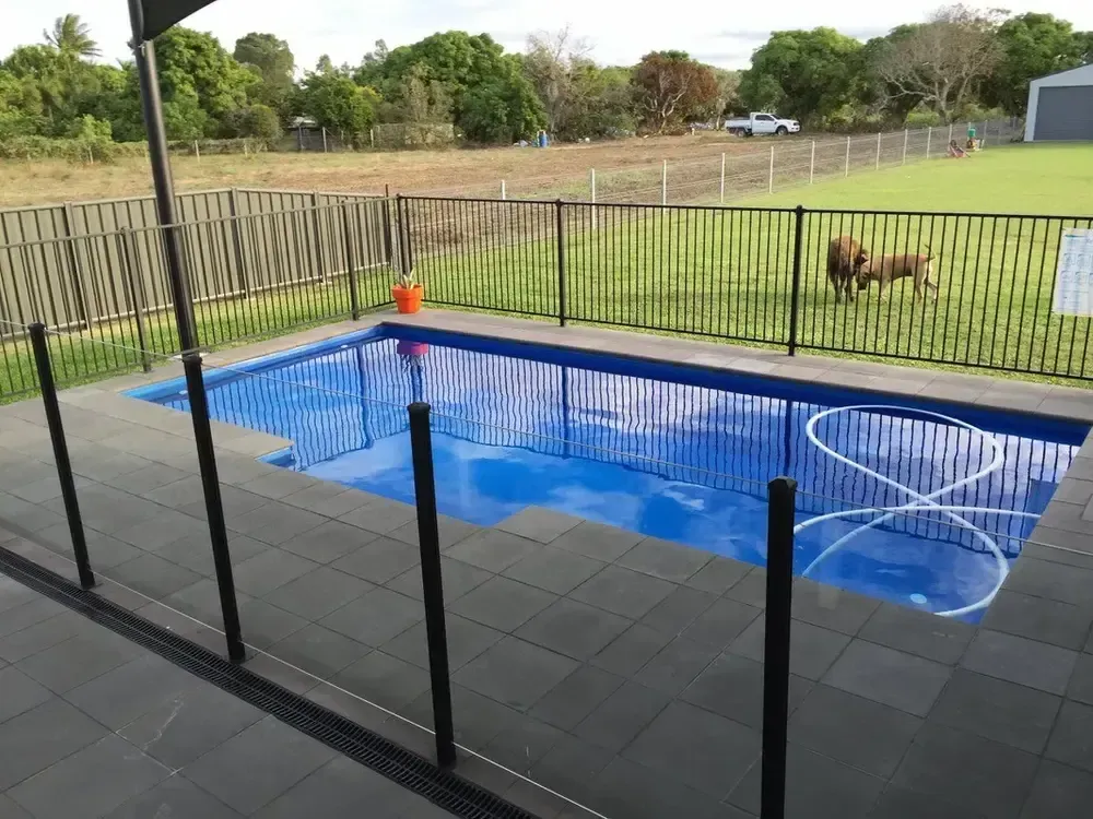 A Large Swimming Pool Surrounded by Tiles and a Fence — Sun City Pools In Hyde Park, QLD