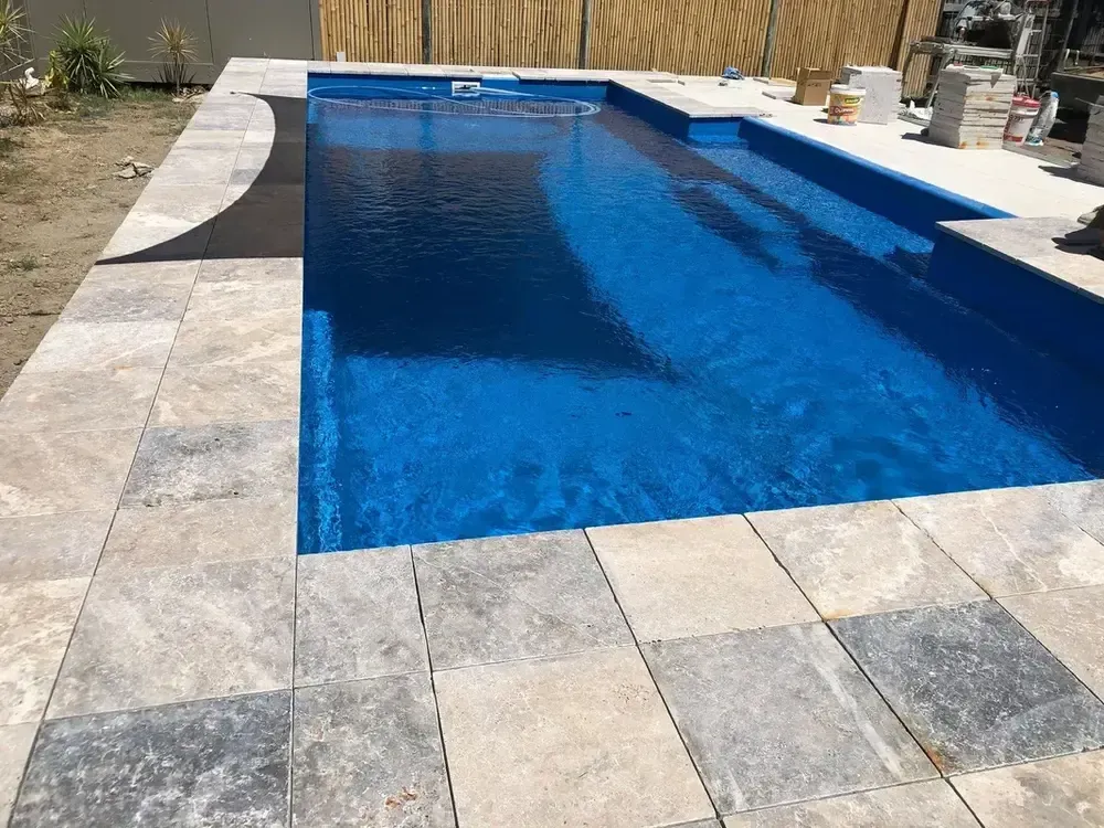 A Large Swimming Pool Surrounded by Tiles and a Fence — Sun City Pools In Hyde Park, QLD